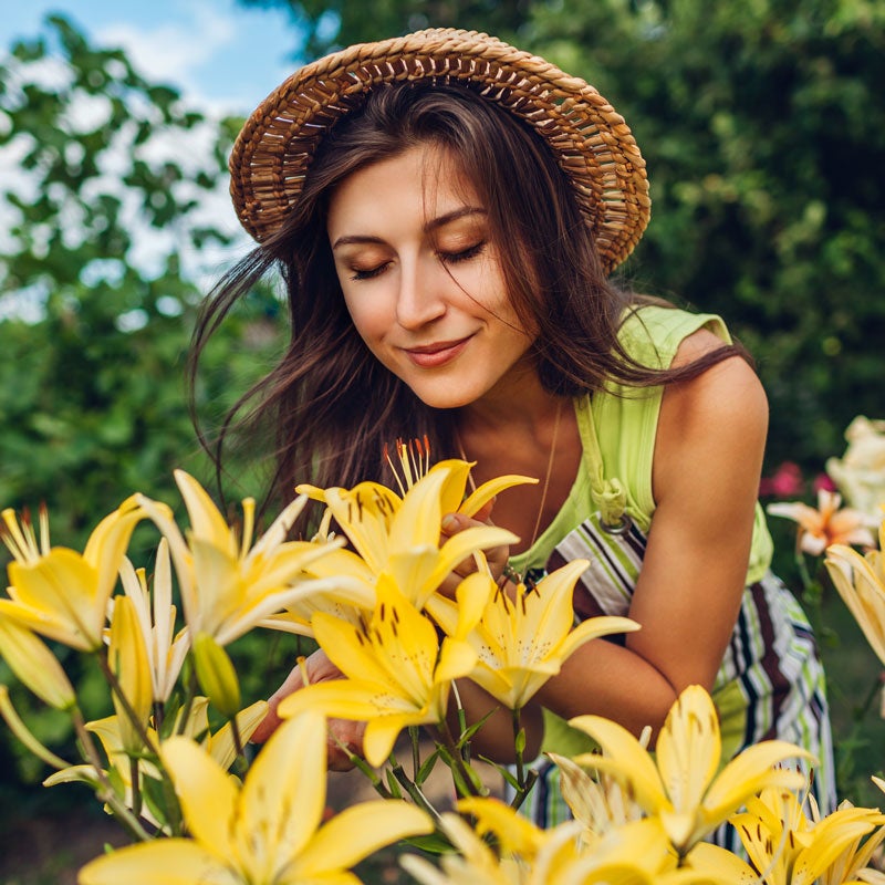 A woman feeling pleasure in the fragrance of fresh garden flowers in Jupiter, FL.