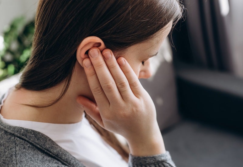 A woman touches her ear, possibly related to Eustachian Tube Balloon Dilation in Jupiter, FL.