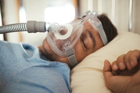 A man asleep with an oxygen mask, illustrating sleep apnea care in Jupiter, FL